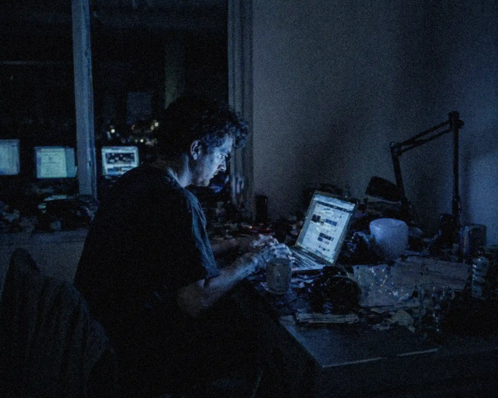 millennials-digital-workspace person working on laptop in dim environment with screen light dominating